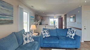 Una sala de estar con dos sofás azules, una mesa de centro y un objeto decorativo con motivos de pavo real.