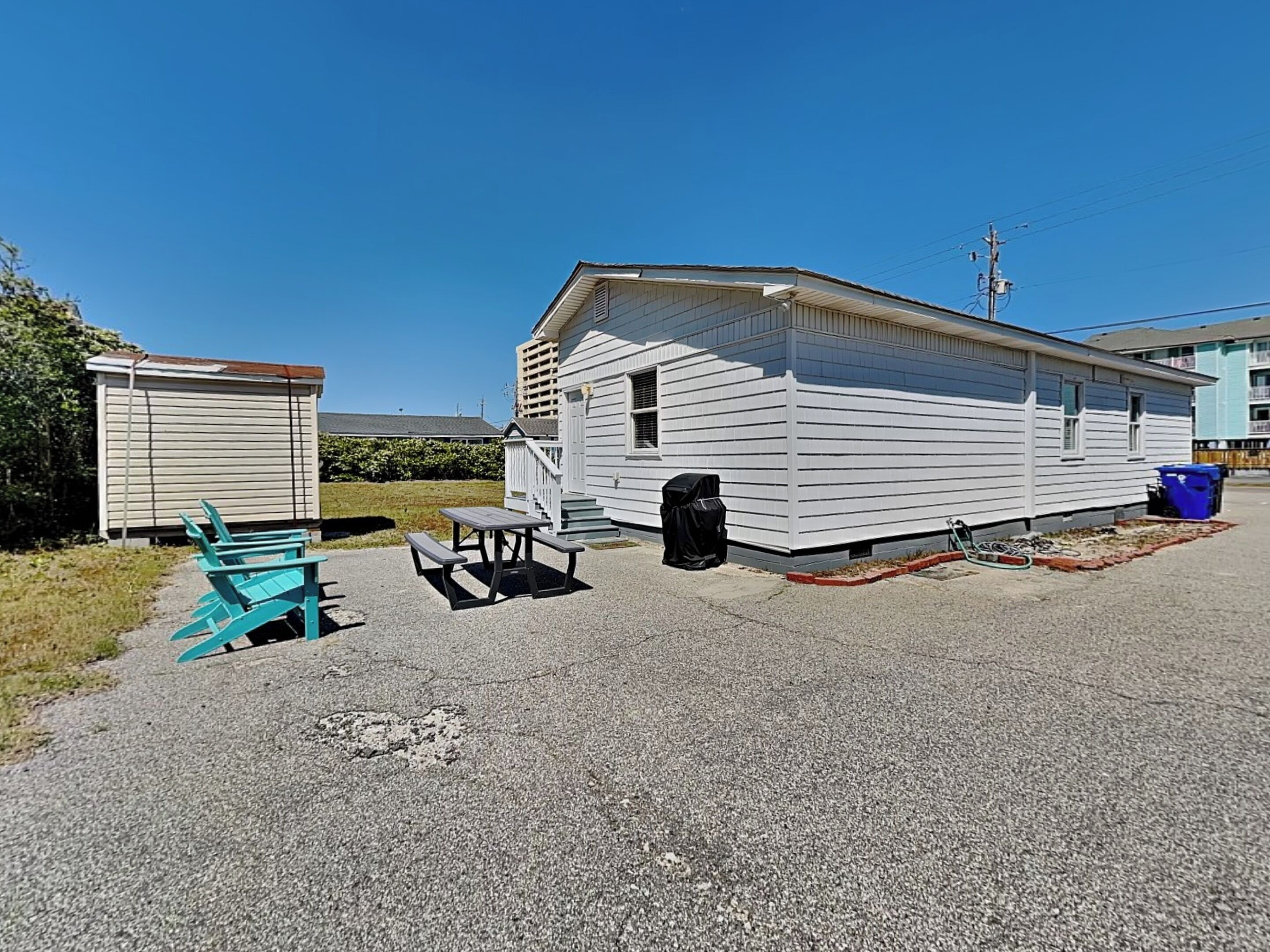 A mobile home with a picnic table and chairs in the driveway.