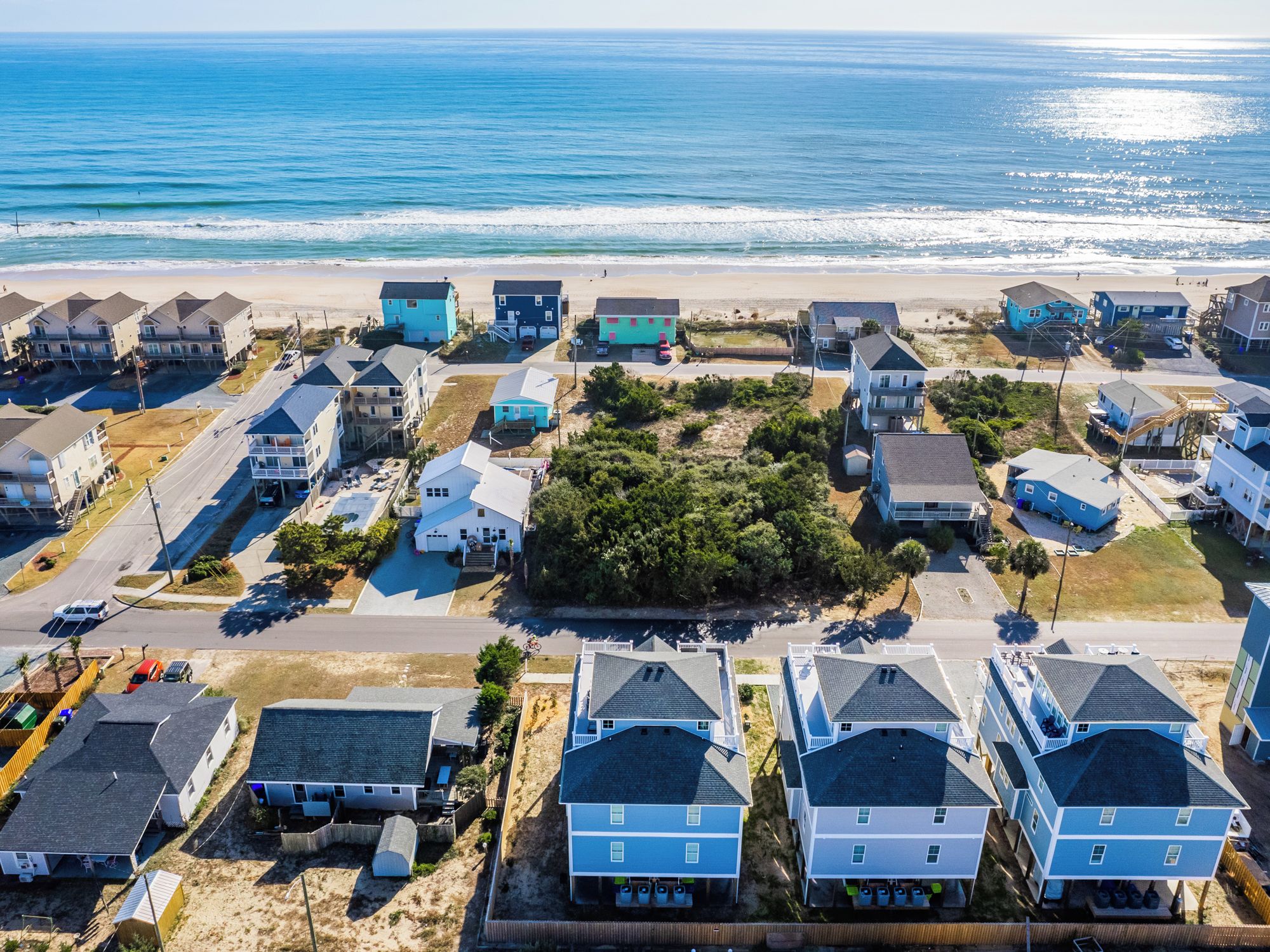 A coastal residential area with multiple two-story houses, some with attached garages, and a beach in the background.