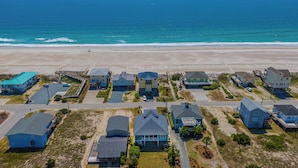 An aerial view of a coastal residential area with houses, a beach, and a clear sky. - The Water Bear by Topsail Realty (Holly Ridge)