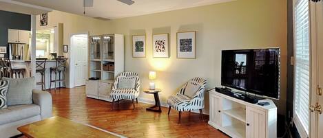 A living room with a sofa, armchairs, a coffee table, a TV, and a ceiling fan.