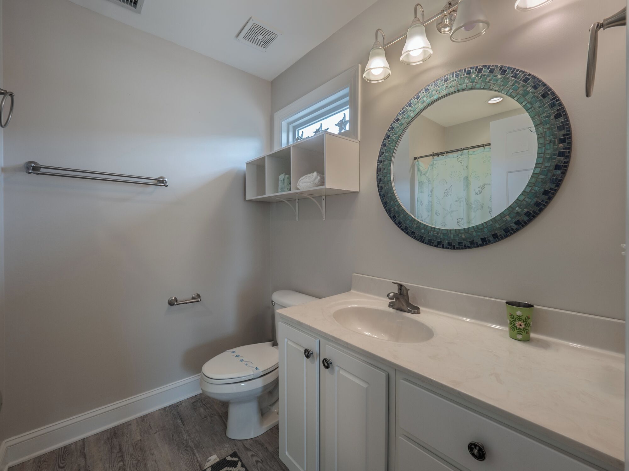 A bathroom with a toilet, sink, mirror, towel rack, and a shower area.