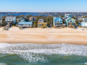 A beachfront property with multiple houses, a sandy beach, and a view of the ocean. - Vintage Vacation by Topsail Realty (Holly Ridge)