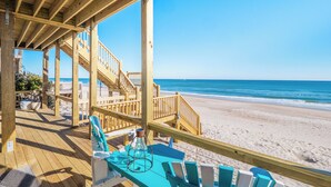 A wooden deck with a table and chairs overlooking a beach. - Vintage Vacation by Topsail Realty (Holly Ridge)