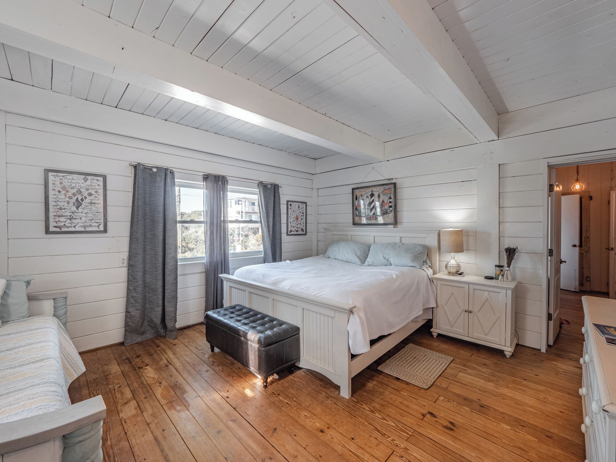 A bedroom with a bed, bedside tables, a bench, and a window with curtains.