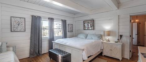 A bedroom with a bed, bedside tables, a bench, and a window with curtains.