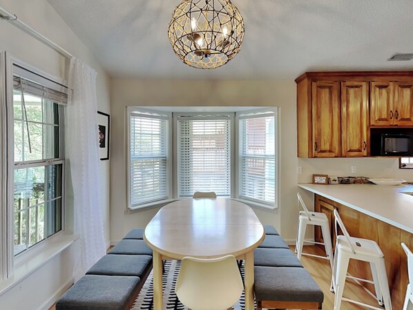 A dining area with a round table, benches, and a chandelier. - Sea Angels by Topsail Realty (Holly Ridge)