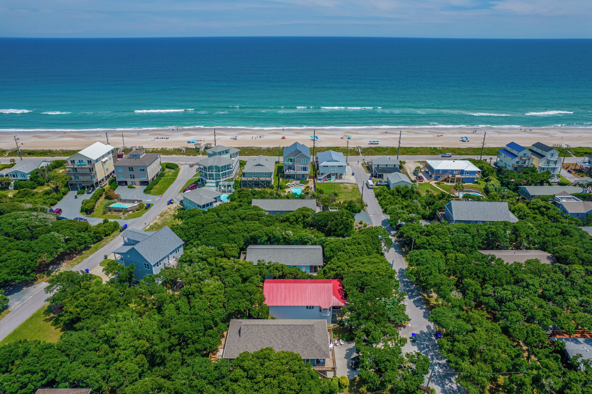 An aerial view of a coastal residential area with houses, a beach, and the ocean.