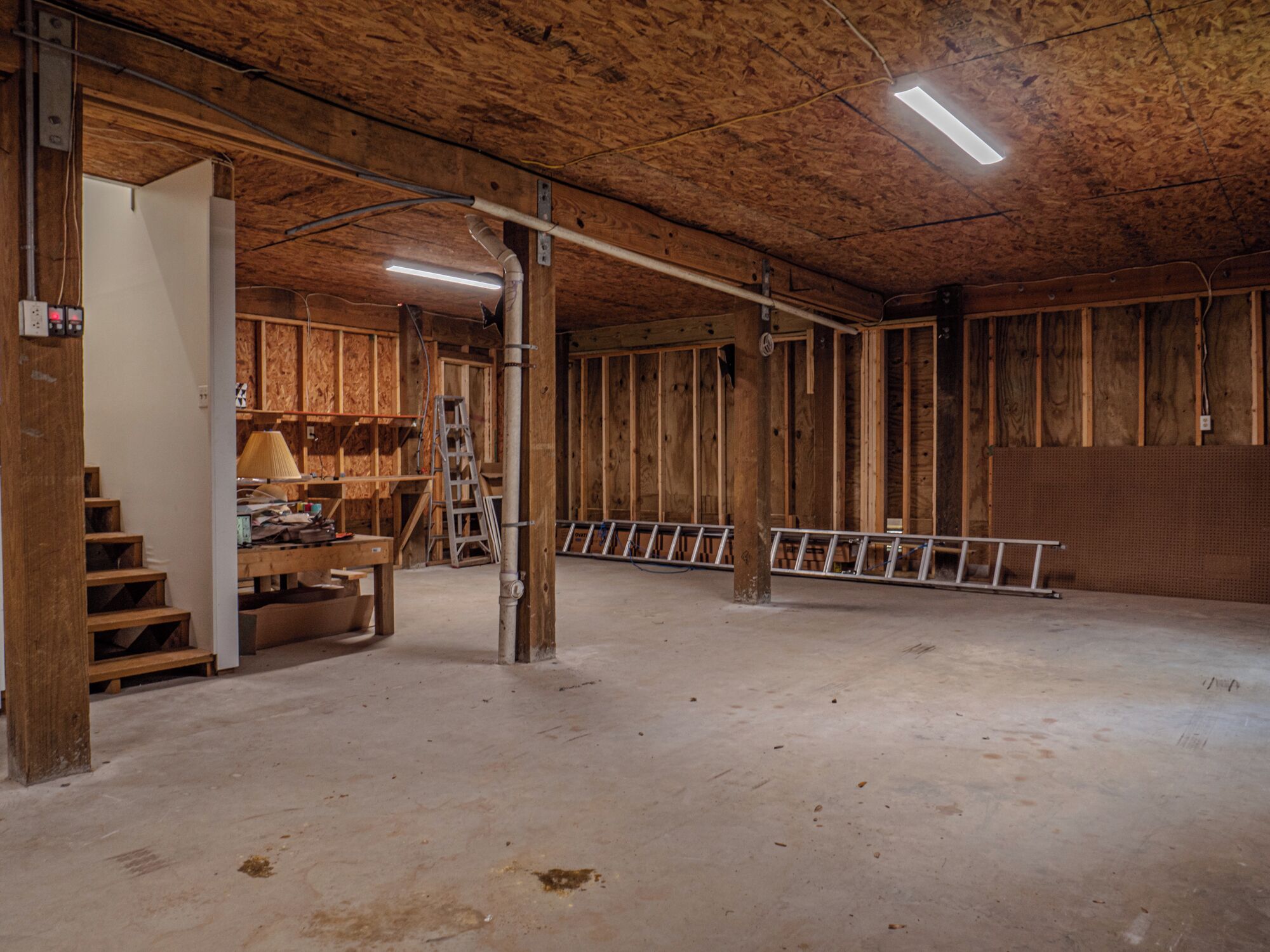 A spacious, unfinished interior with exposed wooden beams and a concrete floor.