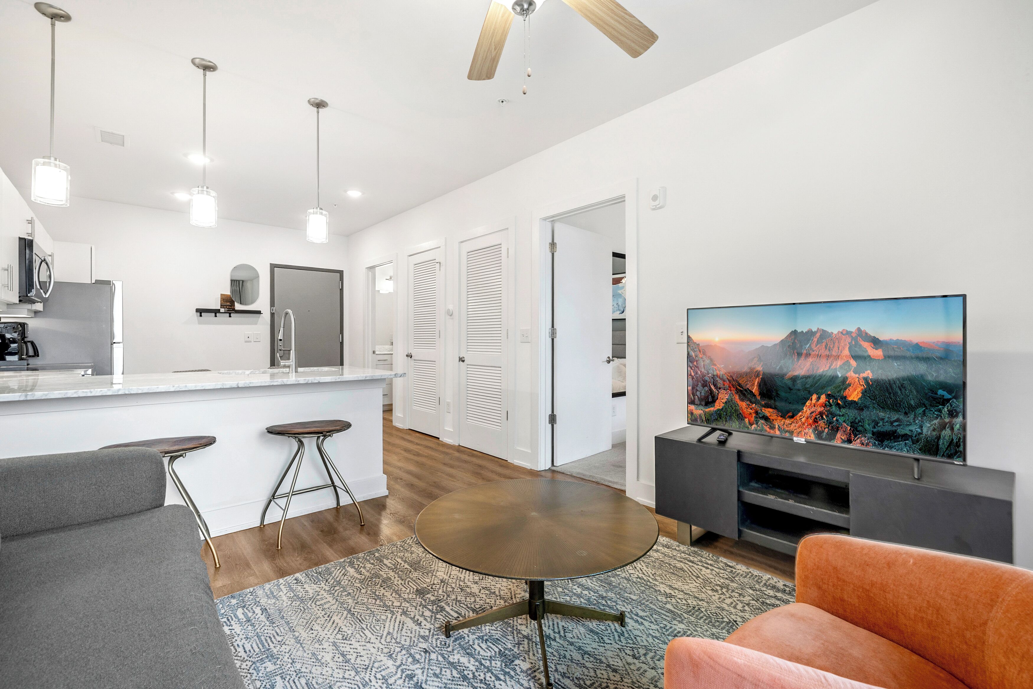 A modern living room with a flat-screen TV, a round coffee table, and a sofa.