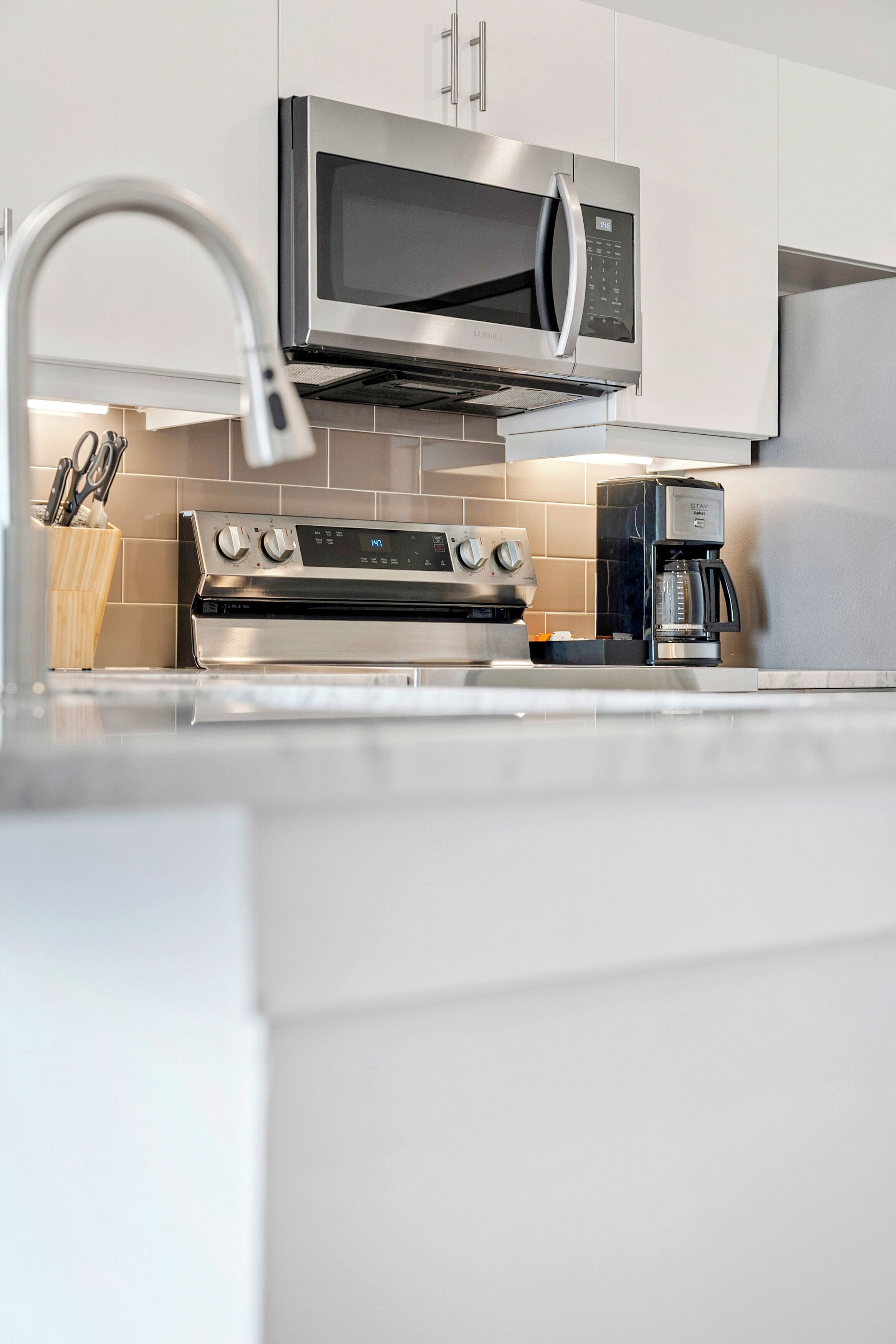 A modern kitchen with stainless steel appliances, including a microwave, oven, and coffee maker.