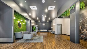 A modern interior with a central seating area, wooden flooring, and green wall accents. - Dorsen Stay (Atlanta)