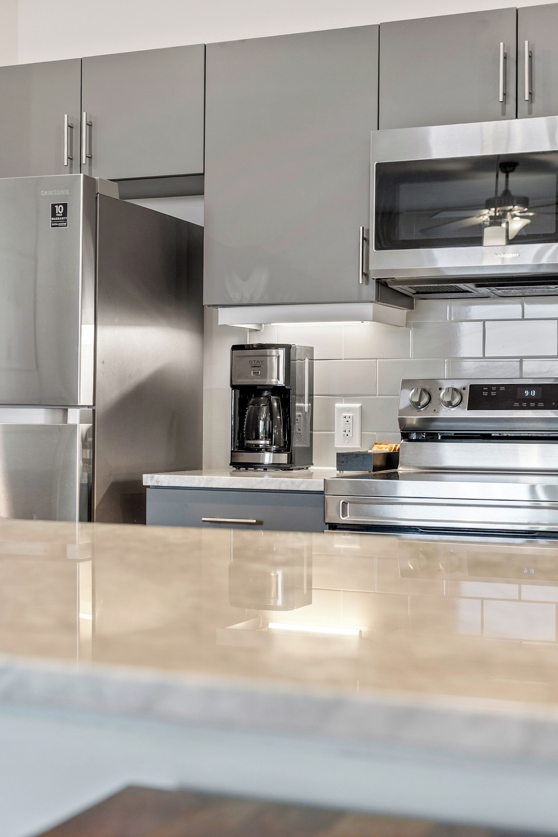 Eine moderne Küche mit Edelstahlgeräten, darunter ein Kühlschrank, eine Mikrowelle, eine Kaffeemaschine und ein Backofen.