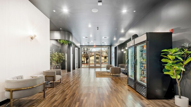 A modern lobby with wooden flooring, seating areas, a refrigerator, and potted plants. - Dorsen Stay (Atlanta)