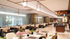 Un moderno vestíbulo de hotel con un mostrador de recepción alargado, varias zonas de estar y grandes ventanales que permiten la entrada de luz natural.