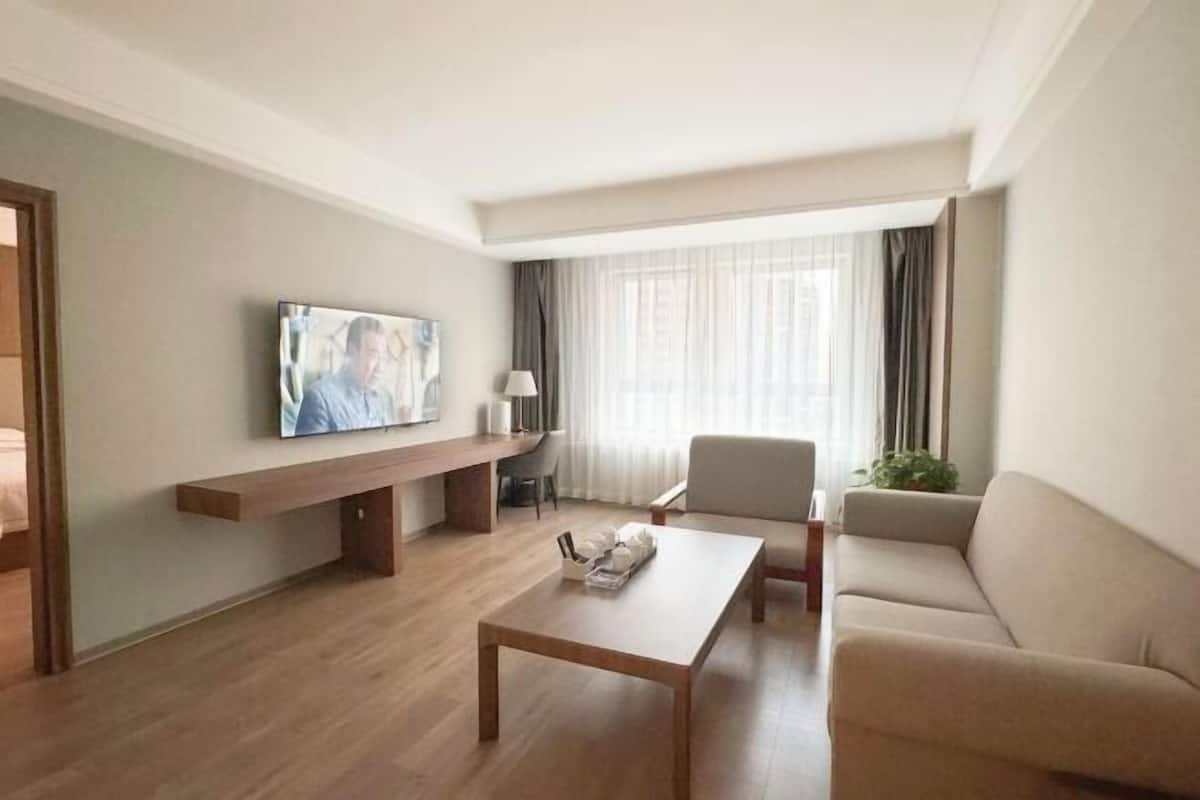 Un salon moderne avec un téléviseur à écran plat, un canapé, une table basse et un banc.