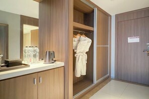 Een badkamer met een houten wastafelmeubel, een spiegel, een handdoekhouder en een kastje met toiletartikelen.