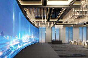 Un salón de conferencias con una pantalla digital curva, una araña y una fila de sillas.