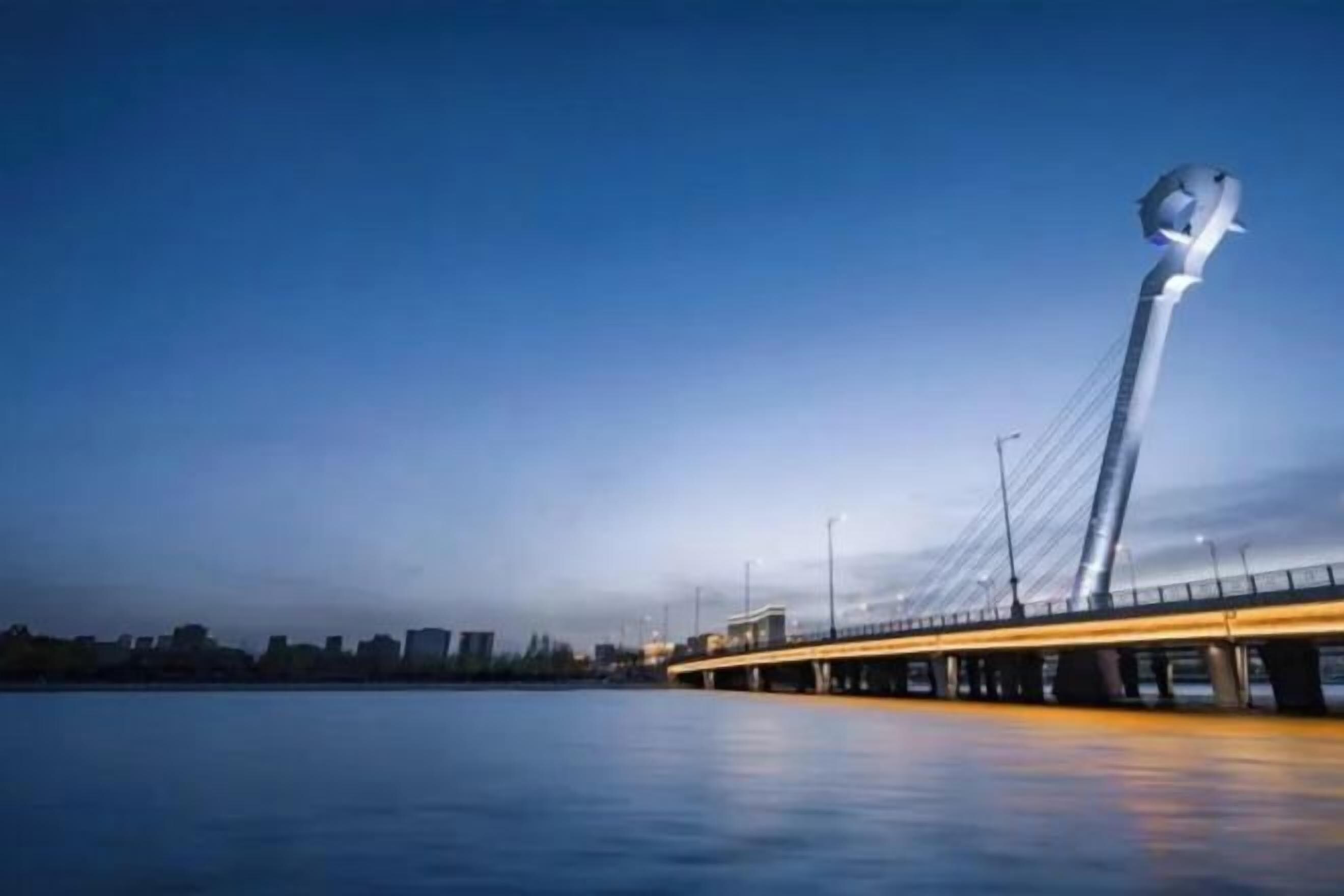 A bridge with a distinctive sculpture at the end, spanning over a body of water.