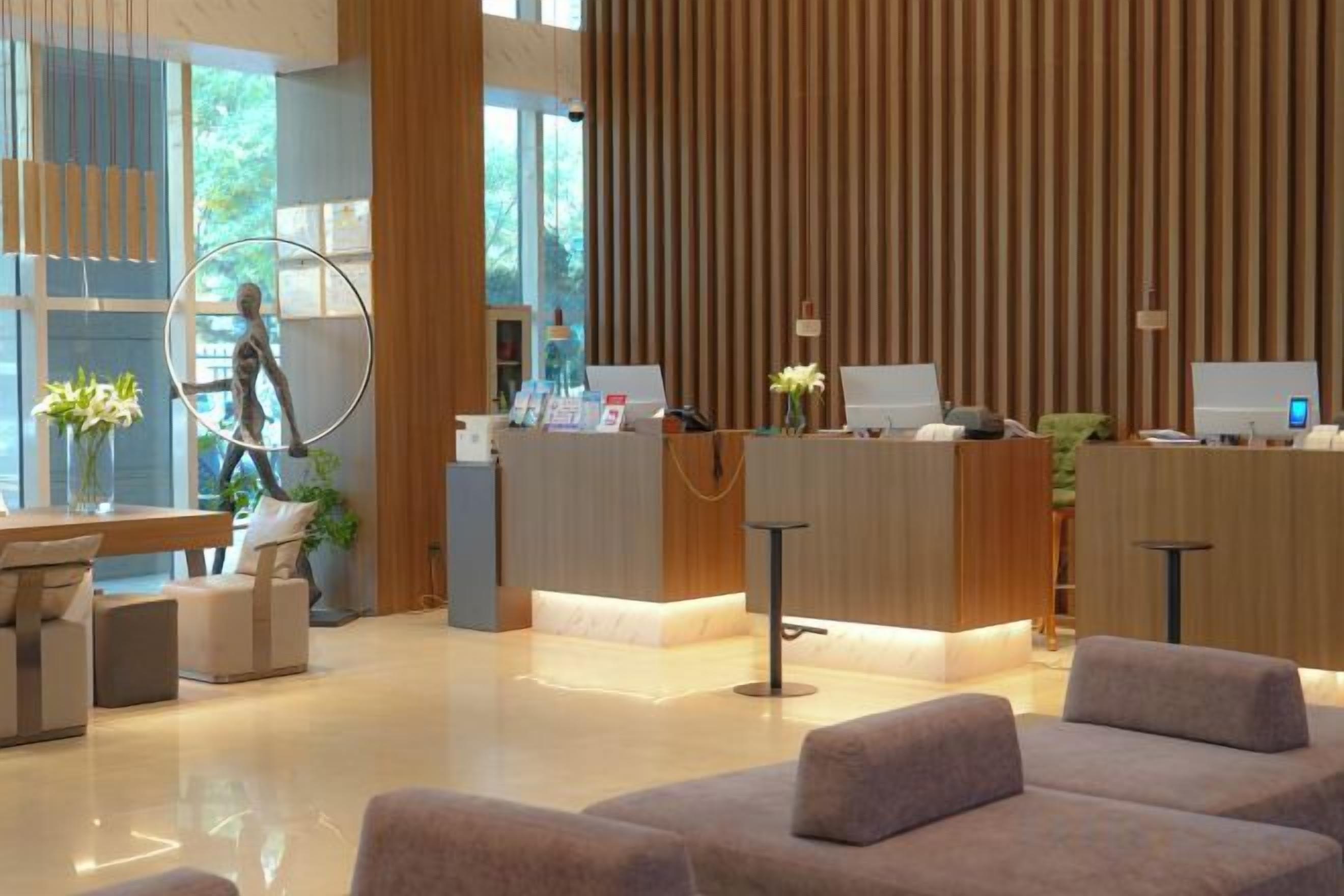 A modern reception area with a wooden reception desk, seating area, and a large window.