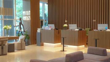 A modern reception area with a wooden reception desk, seating area, and a large window.