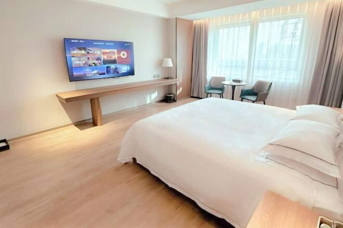 Une chambre d’hôtel équipée d’un lit, d’un téléviseur fixé au mur, d’un bureau et d’une chaise.