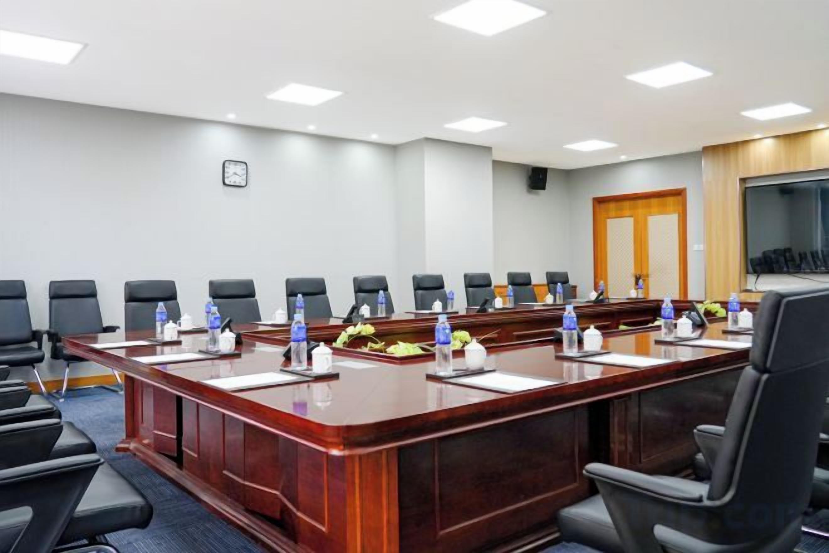 A conference room with a long table, multiple chairs, and a television screen.