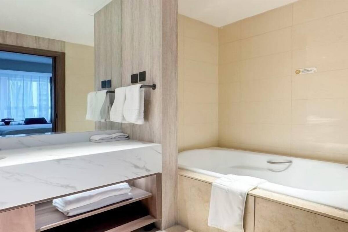 Une salle de bain moderne avec un meuble-lavabo en marbre, une baignoire et un grand miroir.