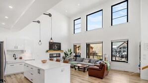 A spacious living area with a large island, a sofa set, and a view of the outside. - Salt & Stone | Lake/Private Beach | Mountain Views (Invermere)