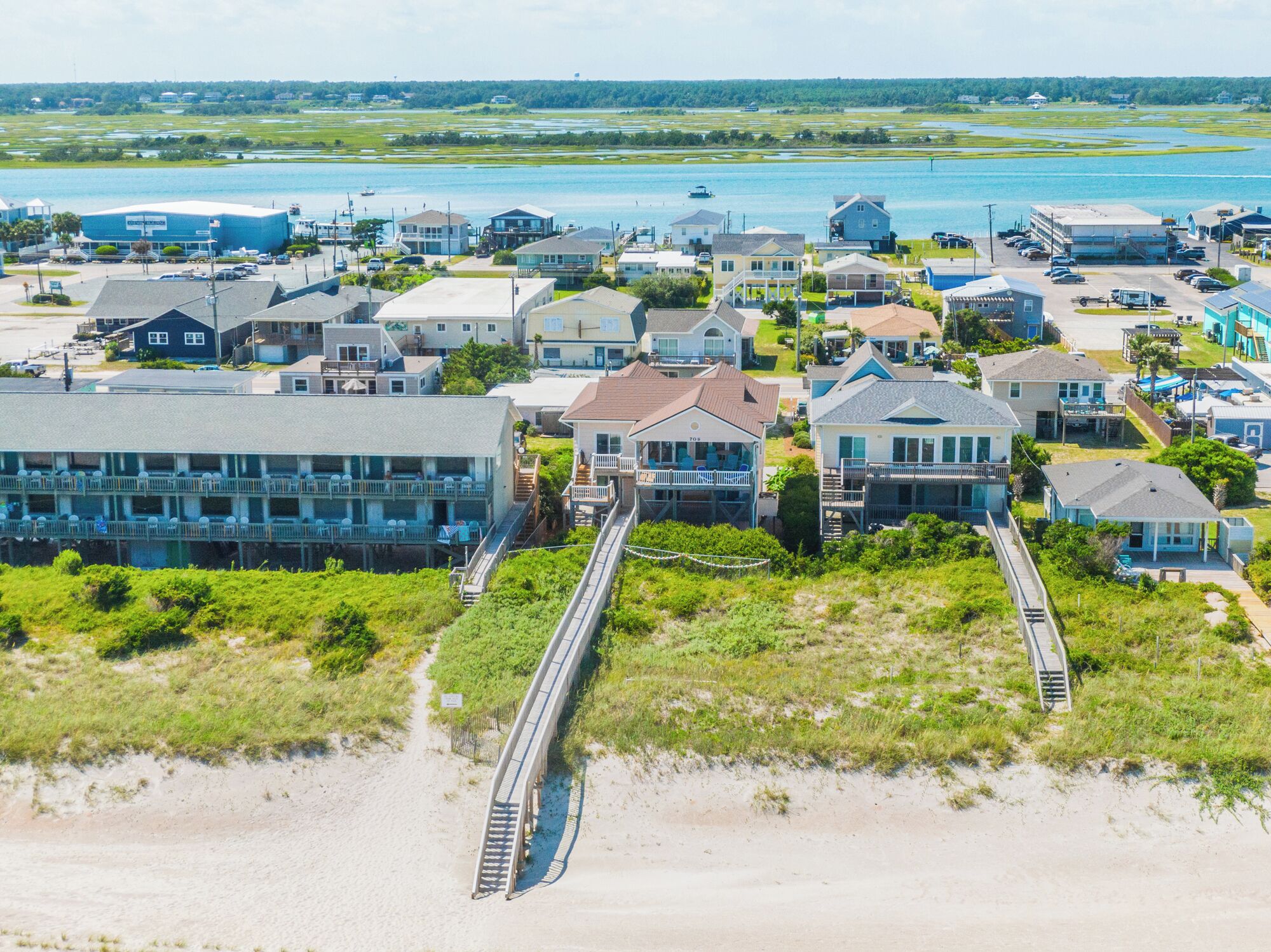 A coastal residential area with houses, a beach, and a pier.