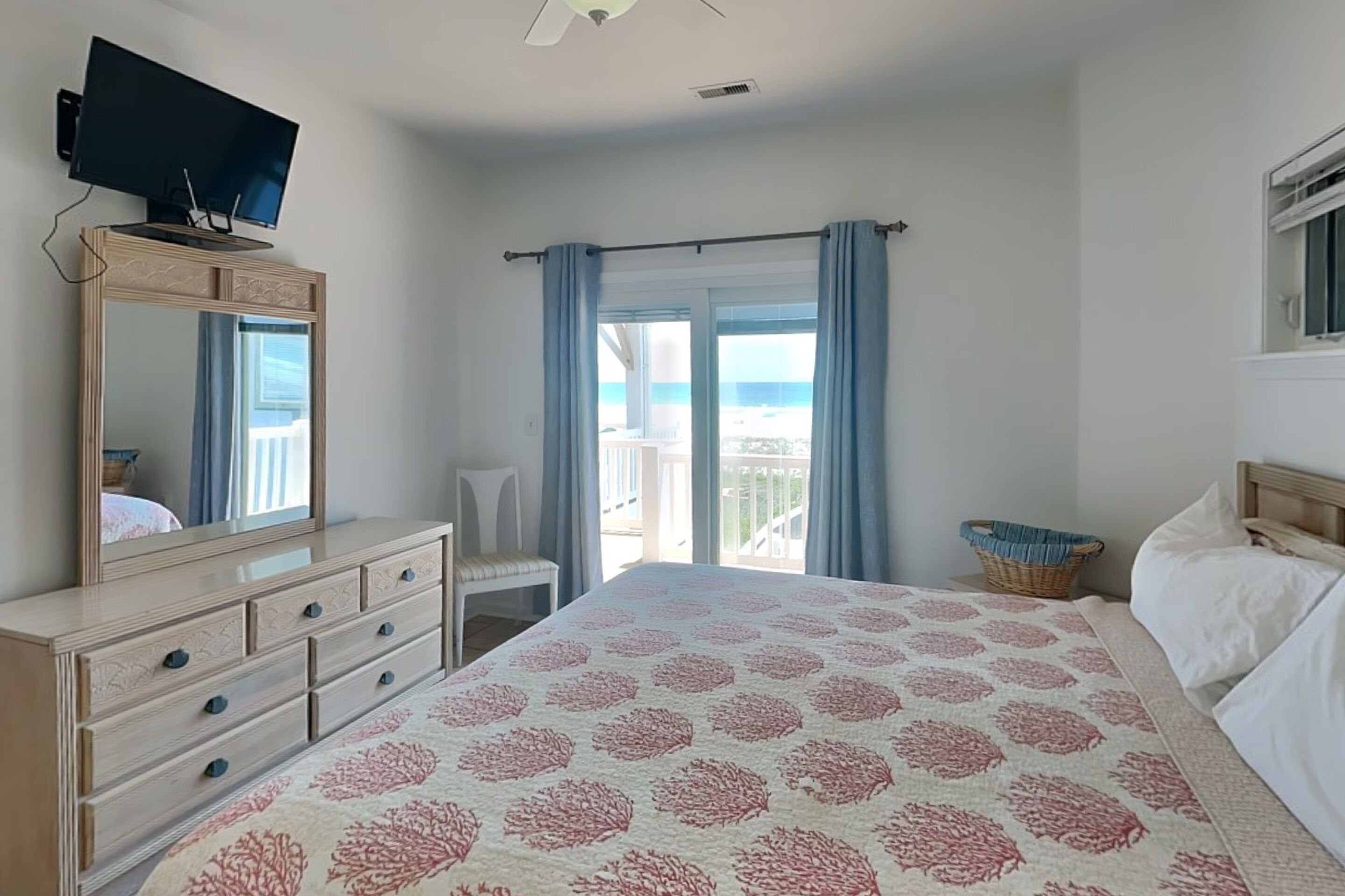 Une chambre à coucher avec un lit, une commode, une télévision et une vue sur la mer.