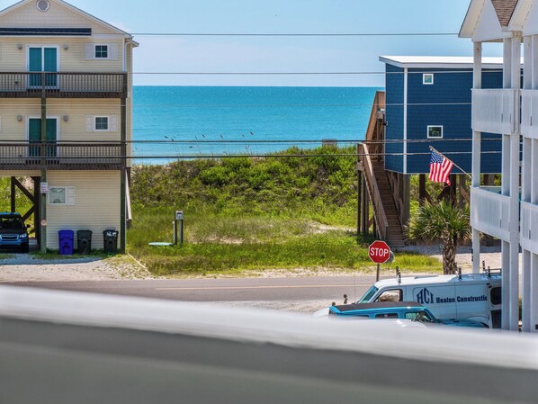 A coastal view with a stop sign, a construction vehicle, and buildings near the beach. - Sunset Cove by Topsail Realty (Sneads Ferry)