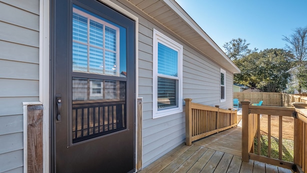 A house with a dark front door, a wooden deck, and a fenced backyard. - Carolina Cottage by Carolina Retreats (Carolina Beach)