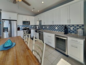 A modern kitchen with white cabinets, a stainless steel refrigerator, a microwave, and a coffee maker. - Shore Thing by Topsail Realty (Holly Ridge)
