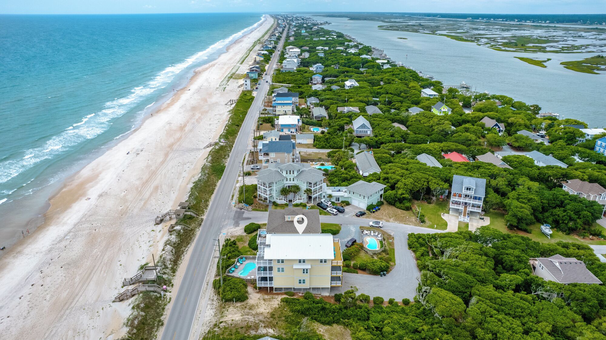 Vista aérea de una zona residencial costera con casas, una playa y una carretera.