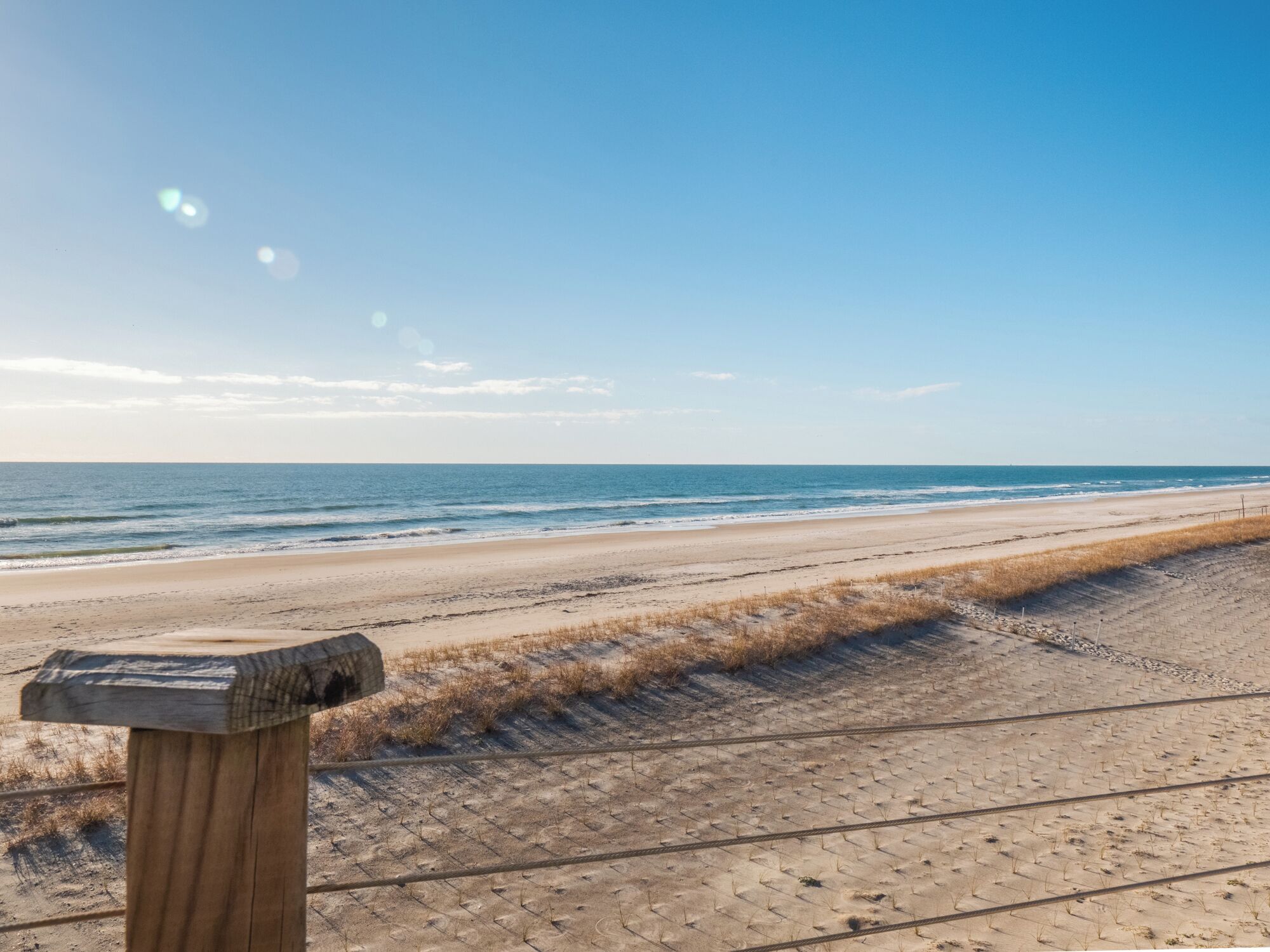 A beach with a wooden post and a paved path leading to the water.