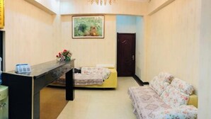 A reception area with a reception desk, a sofa, a bed, and a painting on the wall. - Kangbao Hotel (Xuzhou)