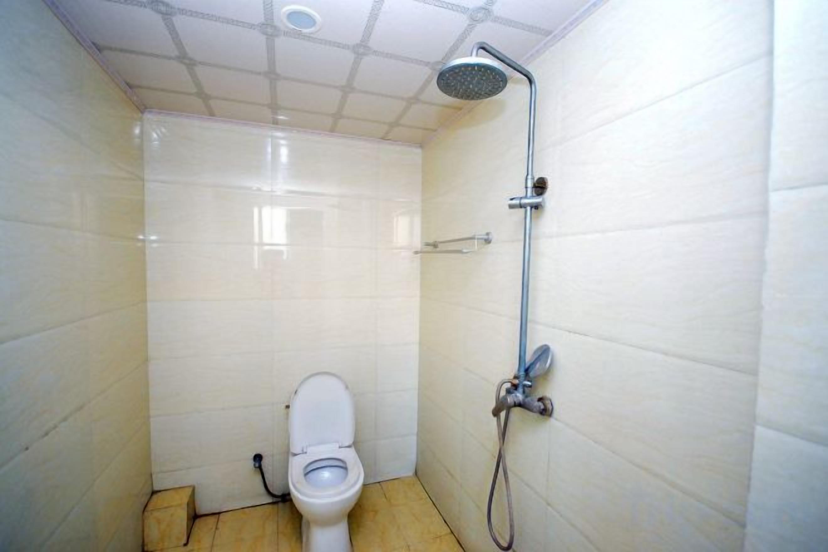 A small, tiled bathroom with a toilet and a shower.