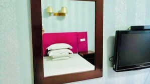 A bedroom with a bed, a TV, and a mirror with a wooden frame. - Kangbao Hotel (Xuzhou)