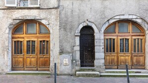Ein Gebäude mit zwei großen Holztüren, eine schwarz und eine braun, mit einer steinernen Fassade.