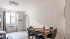 Ein moderner Essbereich mit einem Holztisch, vier Stühlen, einem Deckenventilator und Blick ins Freie durch ein Fenster.