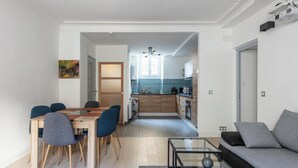 Ein modernes Wohnzimmer mit einer Couch, einem Glastisch und einem Essbereich mit einem Holztisch und Stühlen.