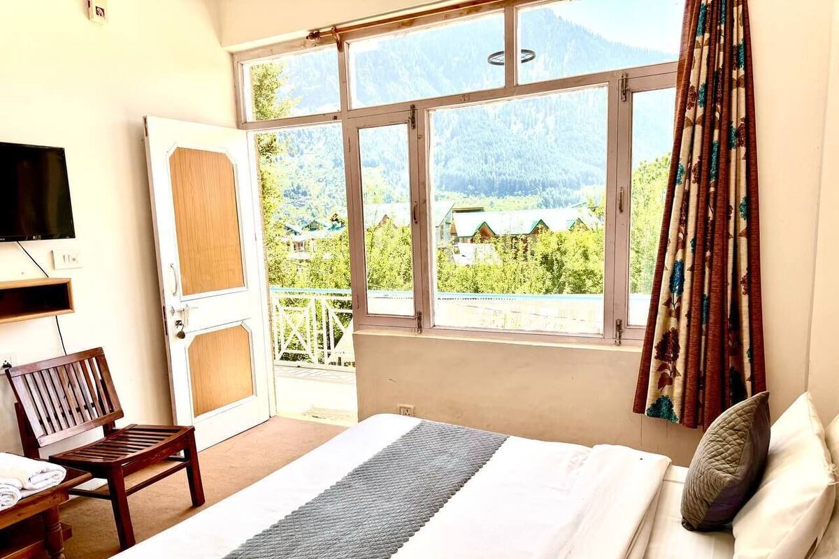 Une chambre d’hôtel avec un lit, une chaise, une télévision et une fenêtre donnant sur la montagne.