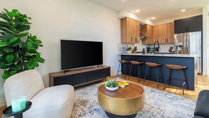 Una sala de estar moderna con un sofá, una mesa de centro, un televisor y una planta grande.