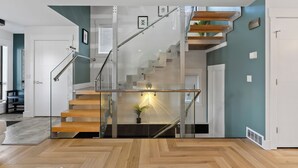 Un intérieur moderne avec un escalier en verre, un plancher en bois et des murs de couleur turquoise.