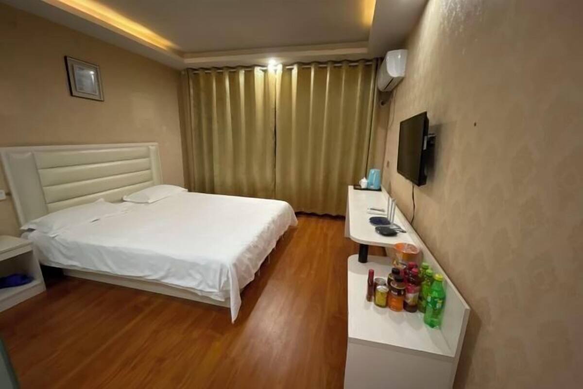 Een hotelkamer met een bed, een nachtkastje met een televisie en een klein plankje met toiletartikelen.