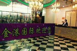 A reception area with a checkered floor, a reception desk, and a chandelier.