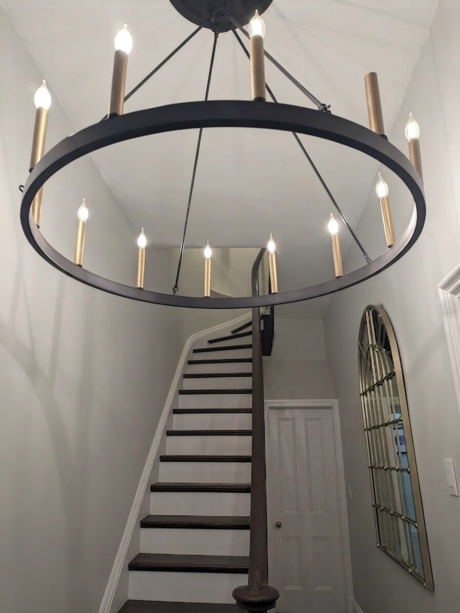 Un escalier surmonté d’un luminaire circulaire au plafond et une fenêtre avec des barreaux.