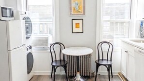 Una cocina compacta con una mesa de comedor, sillas, lavadora y microondas.