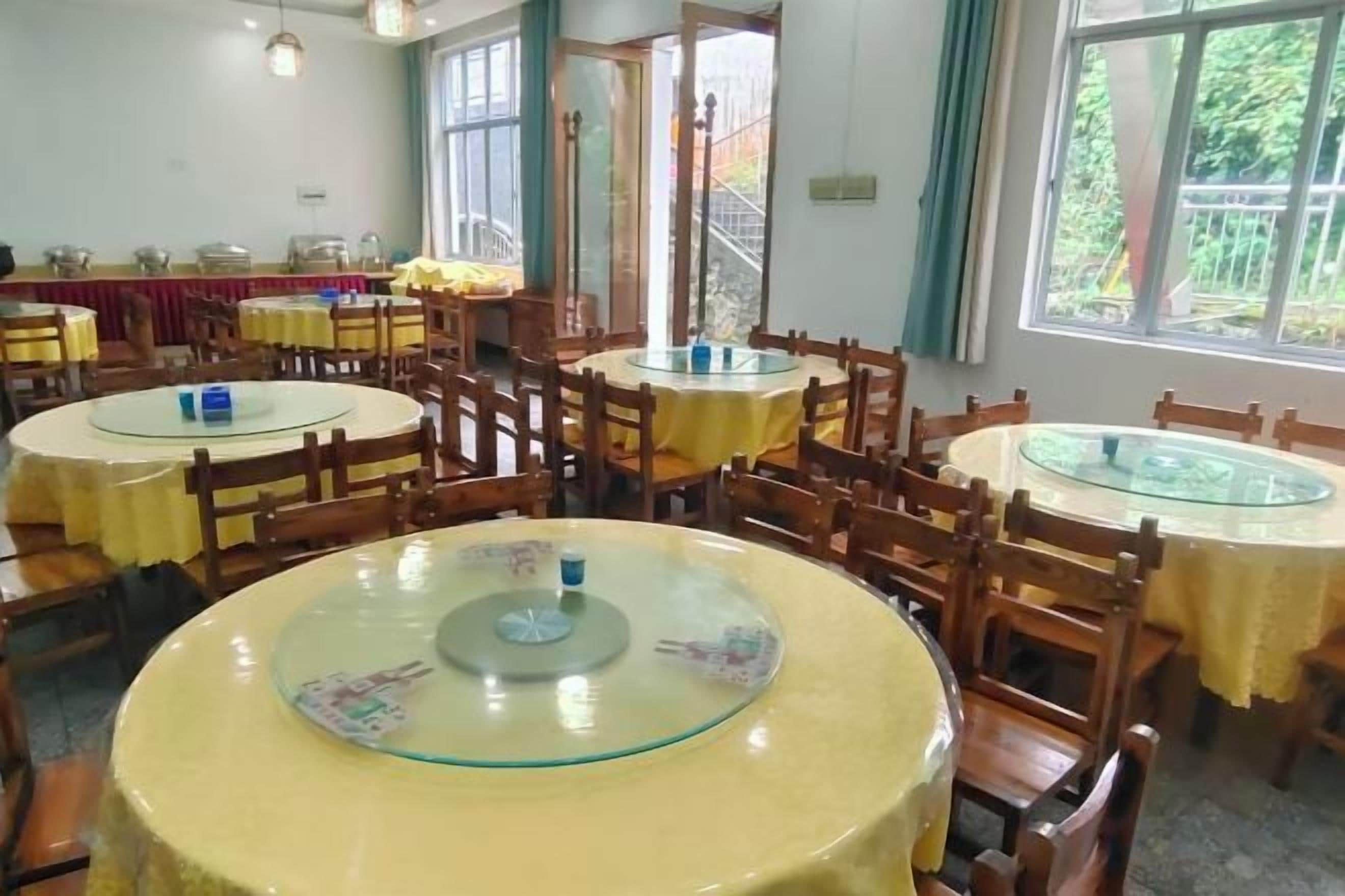Un espace repas avec des tables et des chaises rondes, de grandes fenêtres et une vue sur l’extérieur.